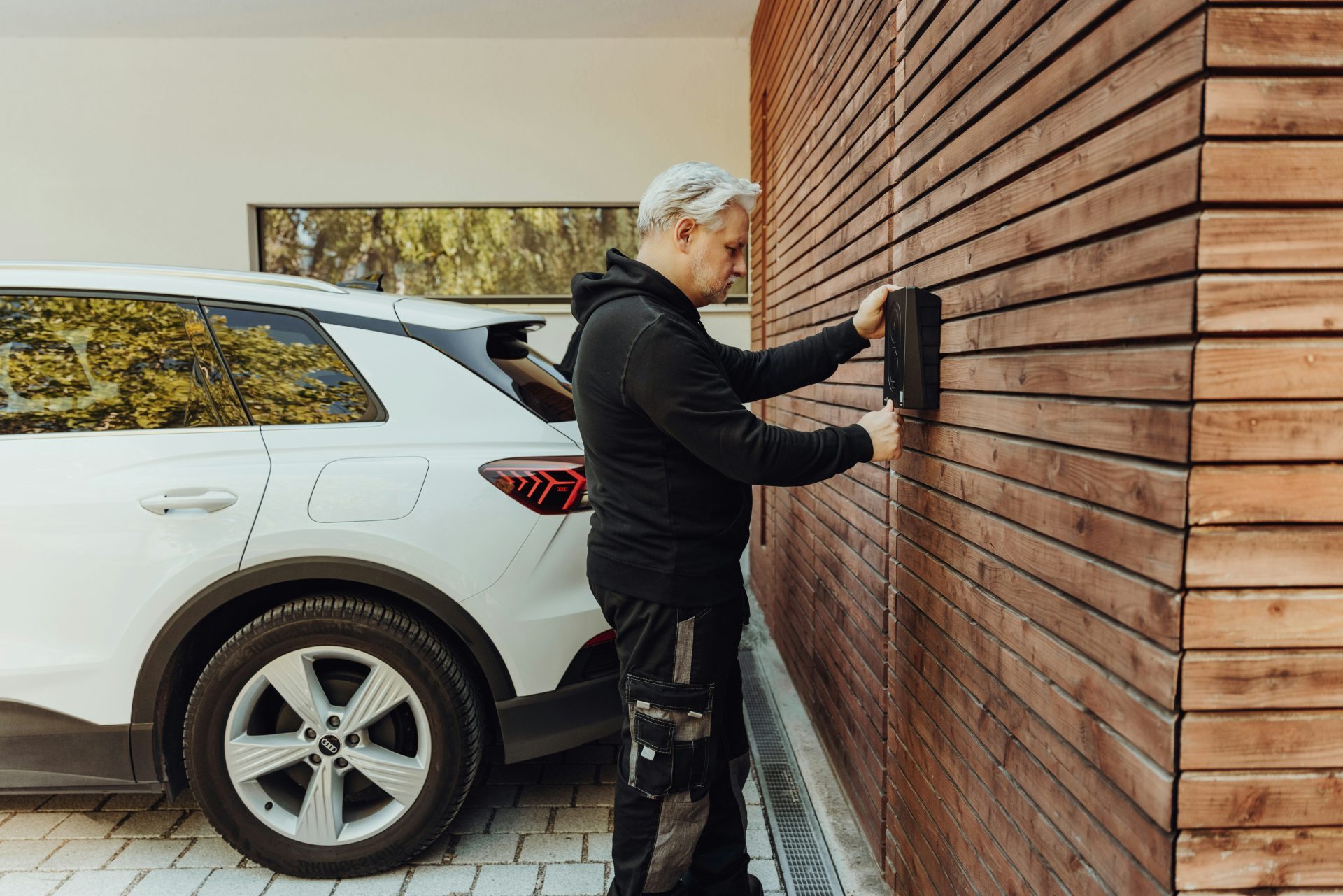 a man in a black jacket and black pants standing next to a white car